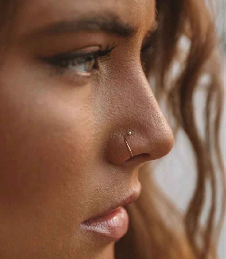 a close up of a woman's face with piercings on her nose