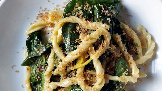 a white plate topped with pasta covered in sauce and vegetables on top of a wooden table