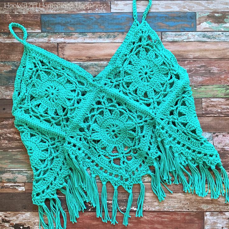 a green crocheted shawl with tassels hanging from it's sides