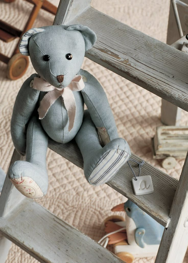 a blue teddy bear sitting on top of a wooden chair next to other toy items