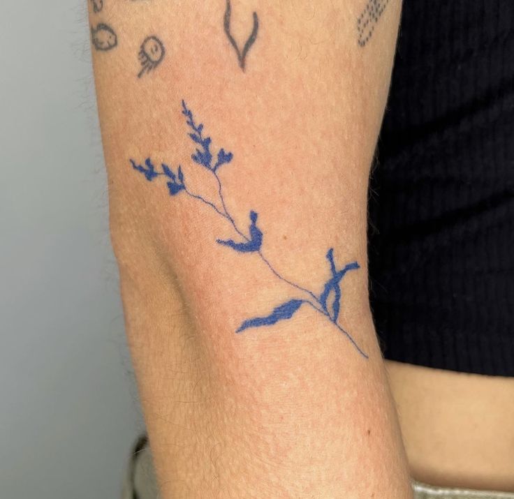 a woman's arm with blue flowers and birds tattoo on the left side of her arm