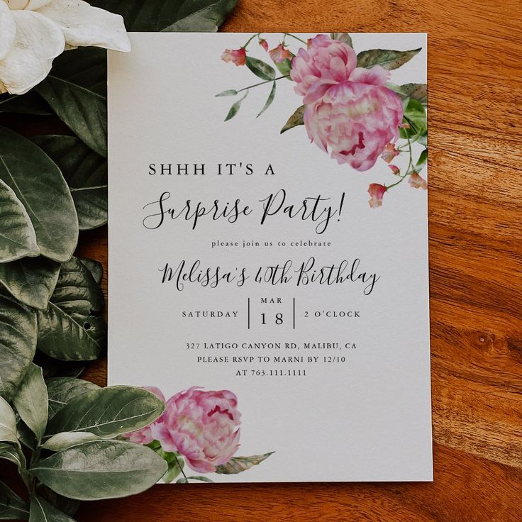 a white card with pink flowers on it and greenery next to the letter'shh it's a surprise party '