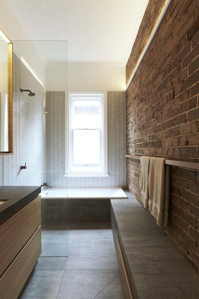 a bathroom with a brick wall and large mirror over the bathtub, along with two sinks