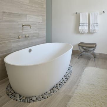 a large white bath tub sitting on top of a wooden floor next to a toilet