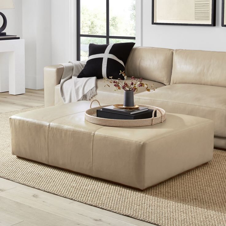 a living room filled with furniture and a coffee table on top of a rug in front of a window