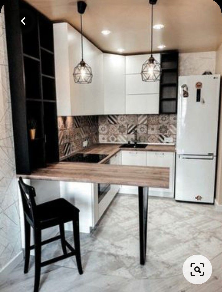 a small kitchen with white cabinets and black counter tops, along with a bar stool