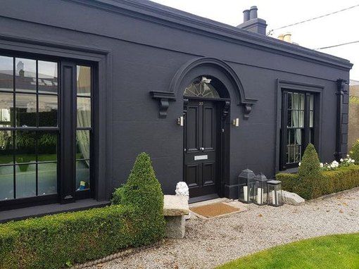 a black house with two large windows and some bushes