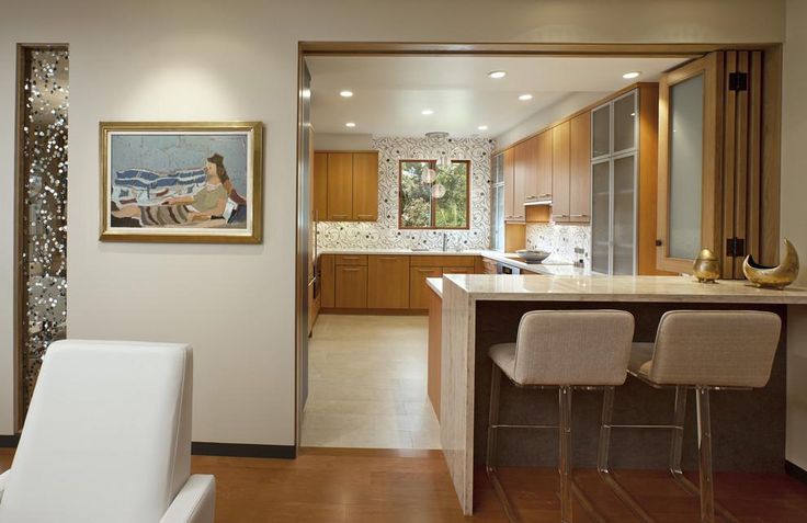 an open kitchen and living room area with chairs, counter tops, and artwork on the wall