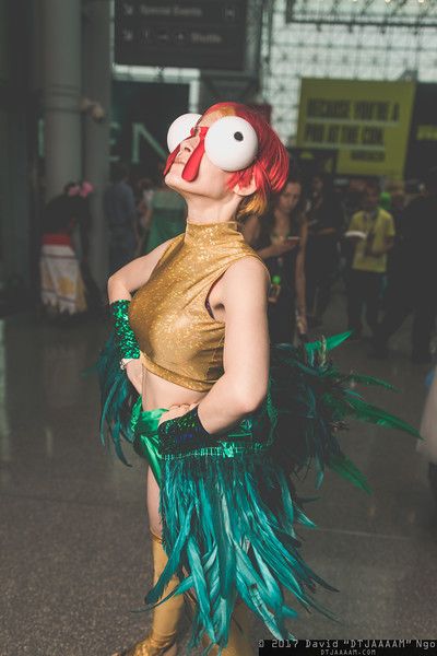 a woman with red hair and green feathers on her head is standing in an airport