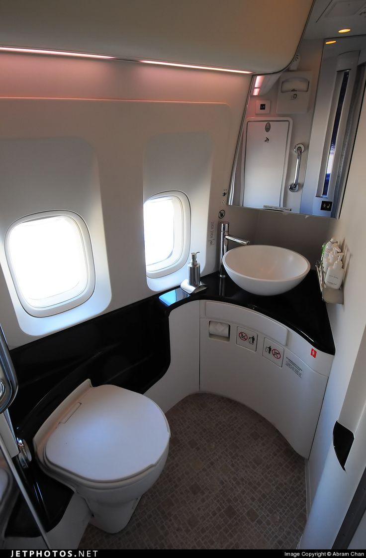 an airplane bathroom with sink, toilet and mirror