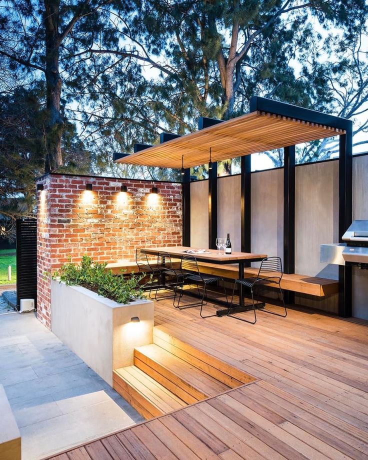 an outdoor dining area with wooden flooring and lighting on the side of the building