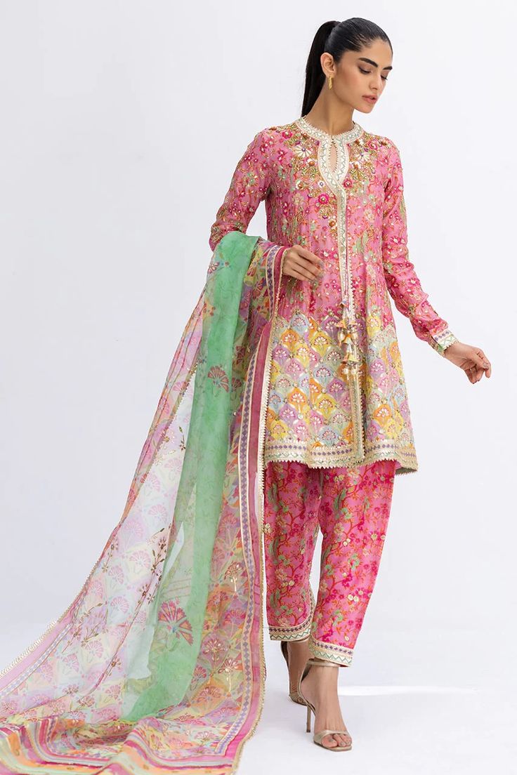 This short, aurora pink angarkha is the embodiment of a classy yet charming festive look. It is rendered with a thoughtful arrangement of zardoze and gota work on a floral-printed khaddi silk, featuring a chatapatti border. A multi-coloured dupatta with gota finishing and a printed shalwar add the final touches to this Pink Anarkali Set For Transitional Season, Pink Anarkali Kurta For Transitional Season, Pink Anarkali Kurta For Seasonal Transition, Pink Silk Sets With Mirror Work, Transitional Anarkali Salwar Kameez In Pink, Pink Designer Wear Unstitched Sharara, Pink Kurta With Gota Work And Traditional Drape, Pink Anarkali Set With Gota Work For Navratri, Pink Bollywood Chanderi Anarkali Set