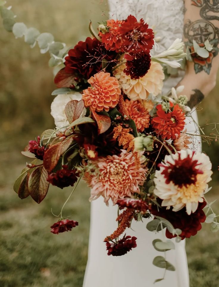 a woman holding a bouquet of flowers in her hands and wearing a white dress with red accents