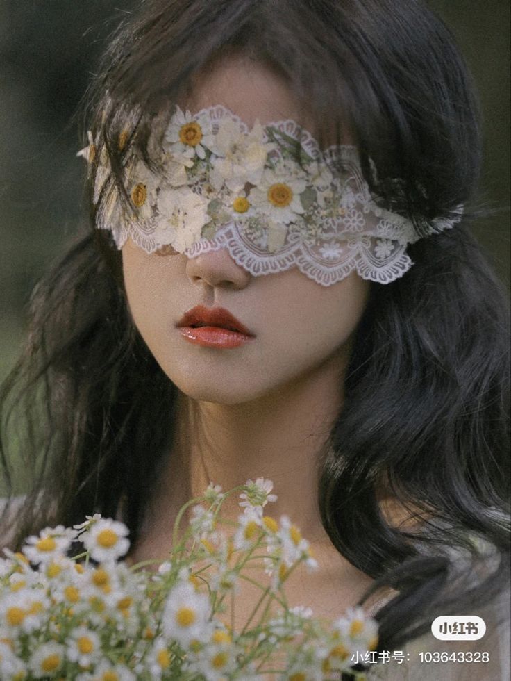 a woman with flowers on her face and lace over her eyes, holding a bouquet of daisies