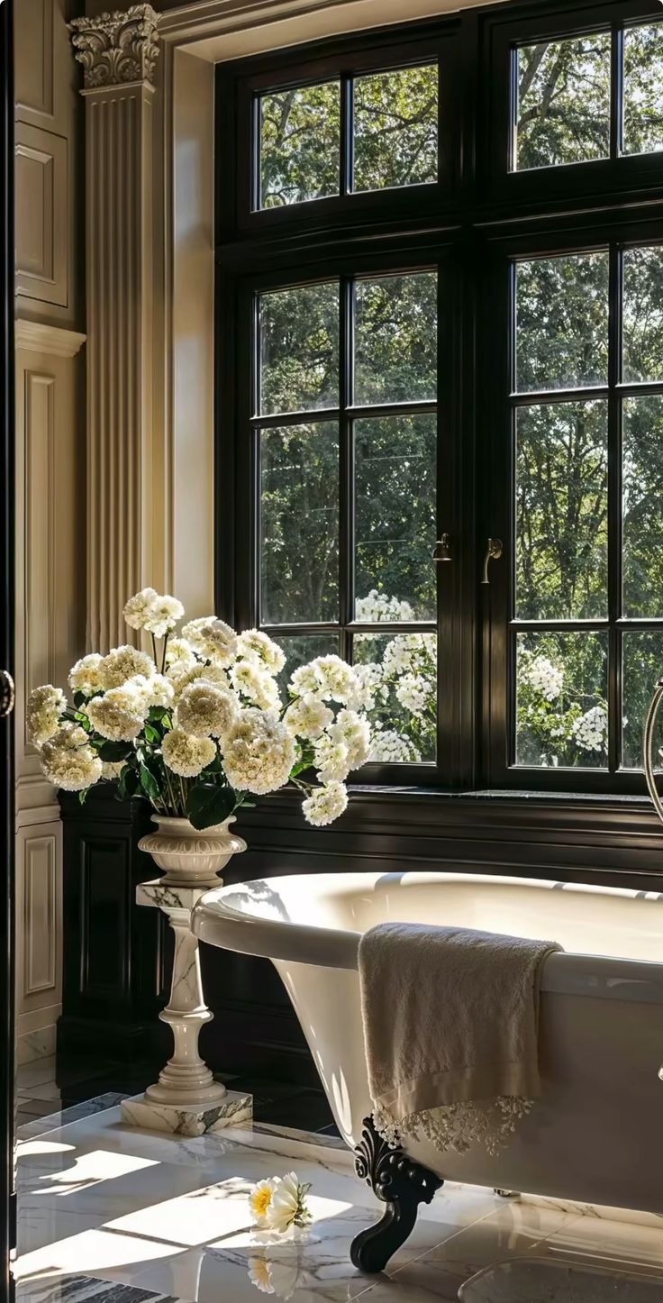 a bath tub sitting next to a window filled with white flowers