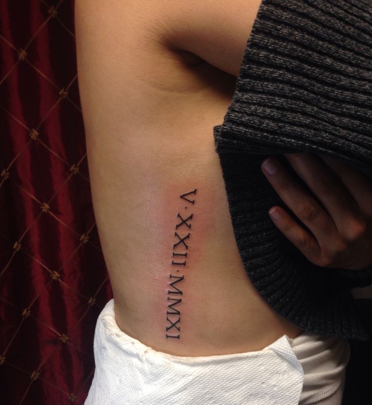 a woman's lower back tattoo with roman numerals on her left side