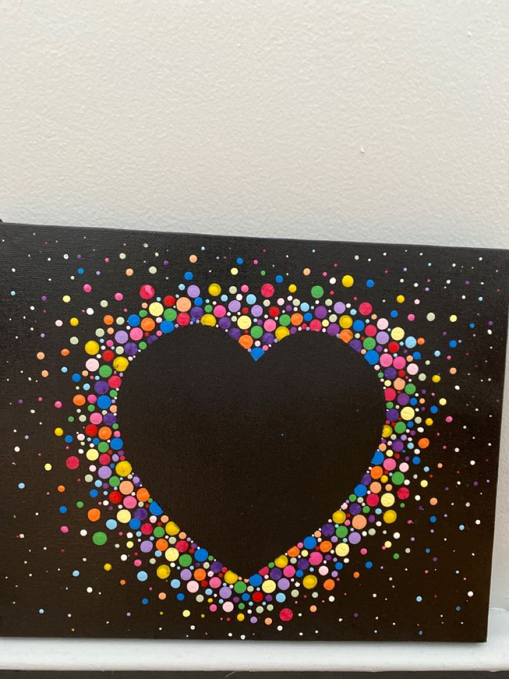 a heart made out of colored dots on a black background with white wall in the background