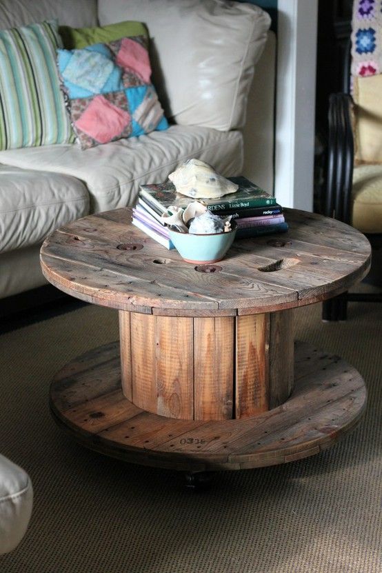 a wooden table with books on it in front of a couch and coffee table made out of pallet wood