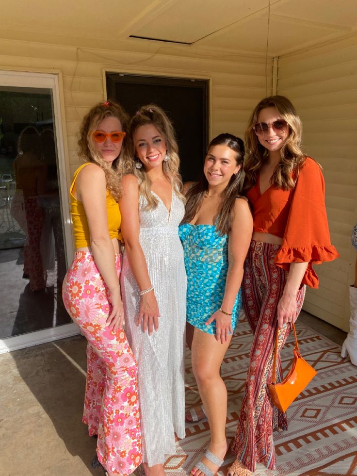 three women standing next to each other in front of a door wearing dresses and sandals