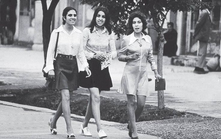 three women walking down the street with bags