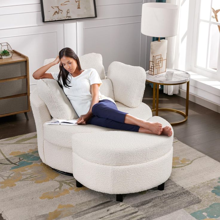 a woman sitting in a chair with her feet up on the floor and reading a book