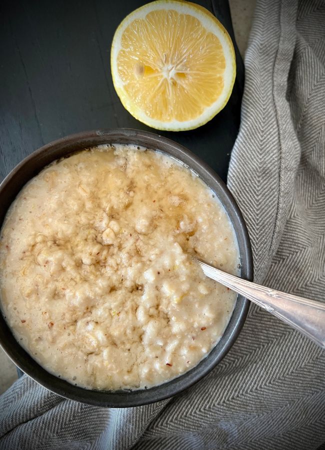 a bowl filled with oatmeal next to an orange slice on a table