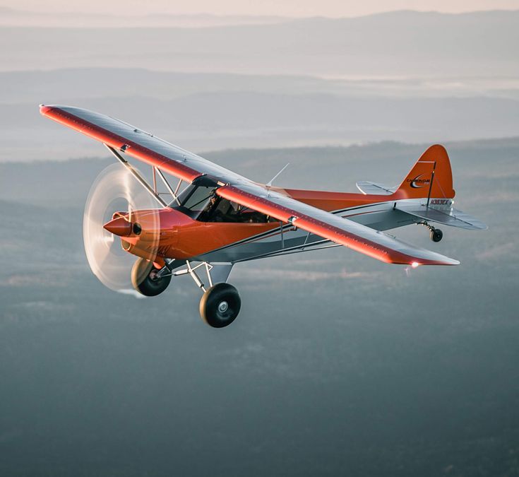 an orange and white airplane flying in the sky