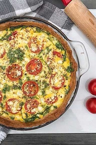 an omelet with tomatoes and spinach in a pan next to a knife