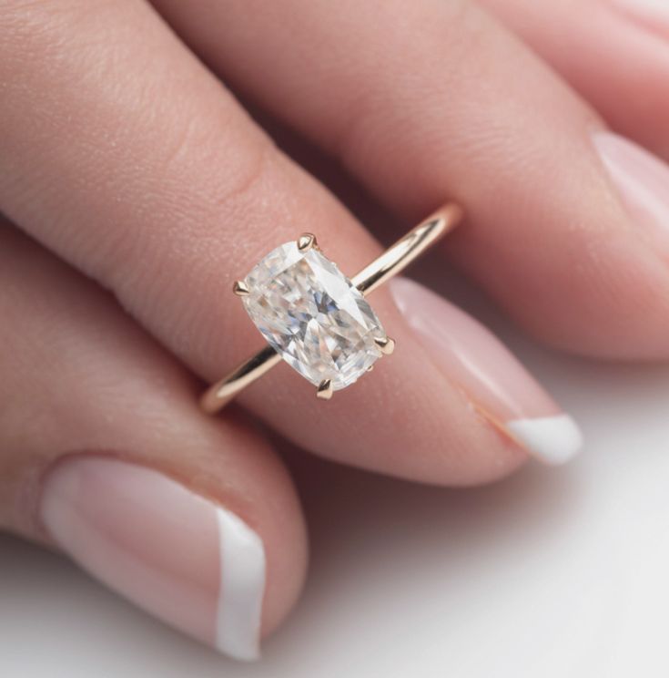 a woman's hand holding an engagement ring with a diamond in the middle, on top of her finger