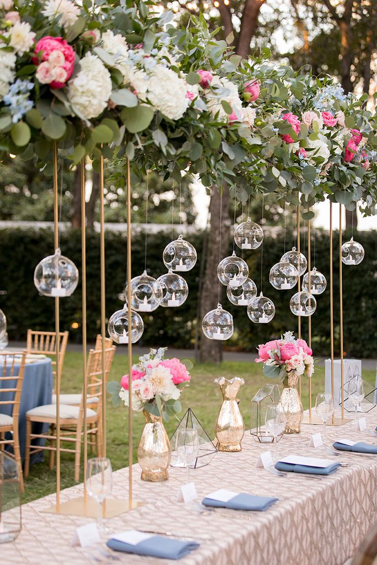 the table is set up with clear vases and hanging glass globes for centerpieces