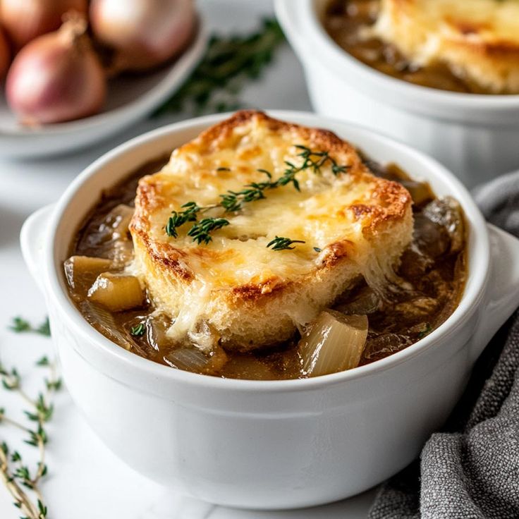 two white bowls filled with food on top of a marble counter topped with onions and gravy