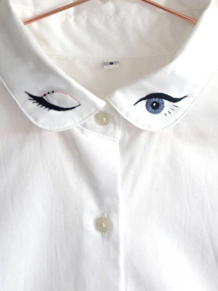 a white shirt with an eye drawn on the front and side of it's collar