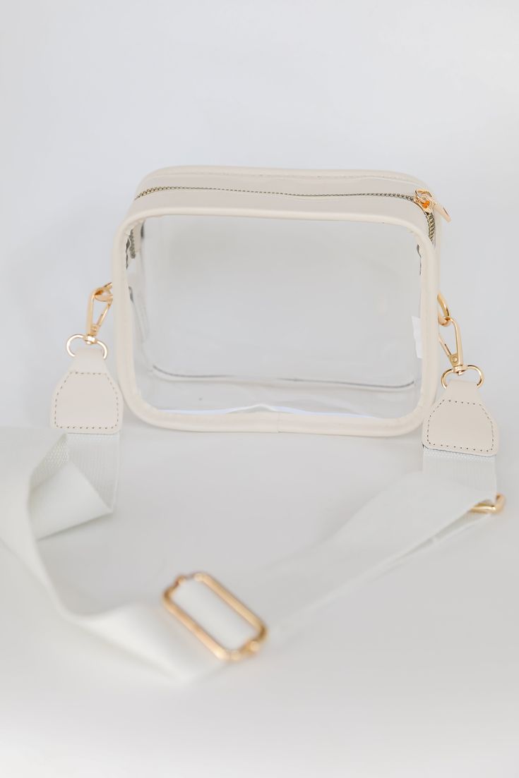 If you're a girl who is always on the go, then the Energetic Aesthetic Clear Crossbody Bag is crucial for stylish success! This chic handbag is designed with a faux leather trim and a clear body. It features a functional zipper closure and a knit removable adjustable crossbody strap. Use the Energetic Aesthetic Clear Crossbody Bag for game days! Available in 2 colors. Faux Leather Trim Clear Body Gold Hardware Removable Adjustable Crossbody Strap Functional Zipper Closure One Size | Length 5" | Energetic Aesthetic, Store Hours, Chic Handbags, Bag Dress, Black Cross Body Bag, Ivory Color, Crossbody Strap, Leather Trim, Leather Trims