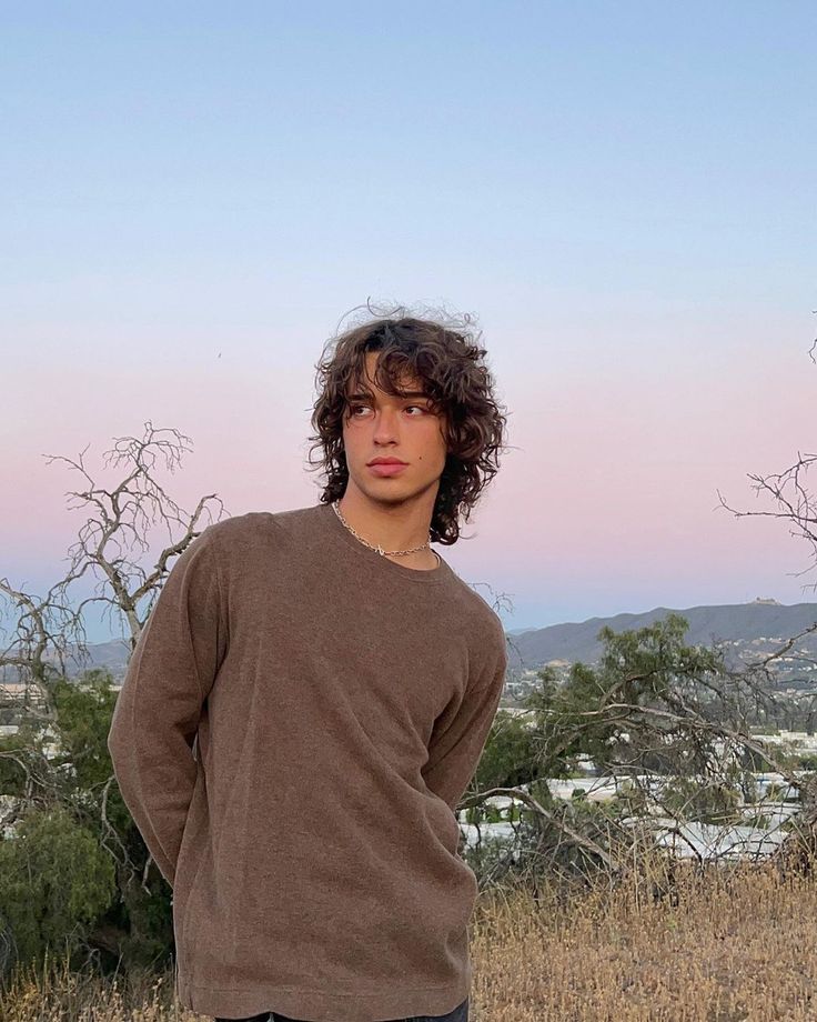 a young man standing on top of a dry grass field