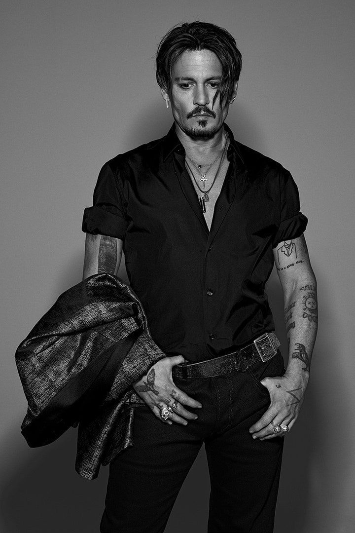 a man in black shirt and pants with tattoos on his arms, holding a bag