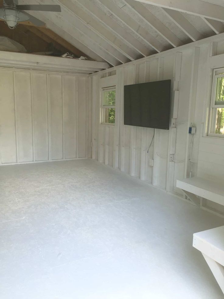 an empty room with white walls and wood paneling on the ceiling is shown in front of a flat screen tv