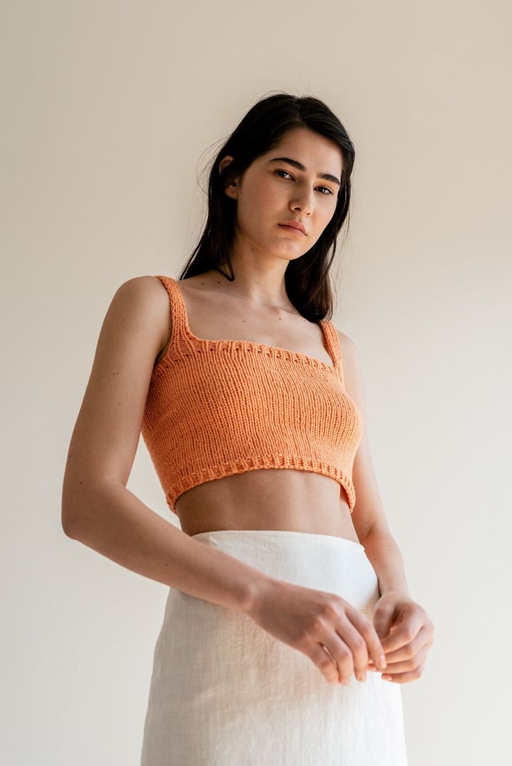 "The Square Neck Crop Top -- our iconic hand-knit cropped top is a year-round wardrobe staple. Thoughtfully designed to elevate your outfits, this versatile piece serves as the perfect blend of elegance and versatility. Handcrafted with utmost care, the Square Neck Crop Top is made from the finest blend of Oeko-Tex cotton, ensuring a luxuriously soft feel against your skin. With its square neckline, wide shoulder straps, and comfortable fit, this top flatters all silhouettes while elegantly framing your décolletage, accentuating your natural beauty with ease. Inspired by the desire for effortless style throughout the year, it can be paired with your favorite linen pants or a gathered long skirt and seamlessly take you from morning strolls to seaside dinners. Every top is made to order. To Fitted Knitted Orange Top, Fitted Orange Knitted Tops, Fitted Cropped Crochet Top, Knitted Cropped Crop Top For Summer, Fitted Knit Crop Top For Beach, Fitted Cropped Knit Top For Beach, Fitted Seamless Orange Crop Top, Orange Fitted Crop Top, Summer Cropped Knitted Tops