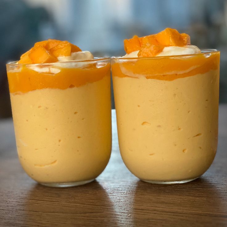 two desserts are sitting on a table, one is orange and the other is white