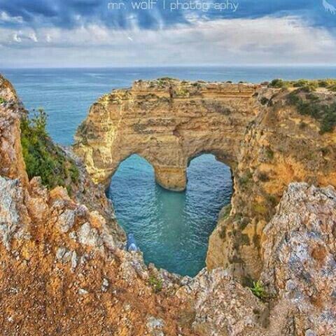 an arch in the rock with water below