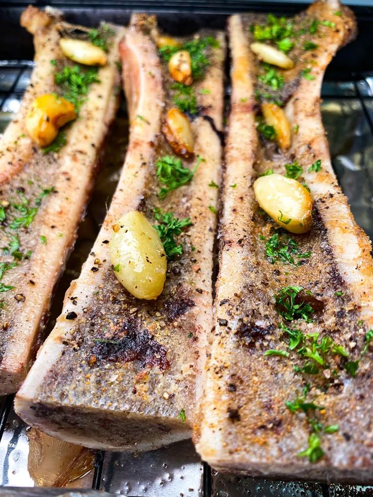 two pieces of meat sitting on top of a pan covered in seasoning next to potatoes