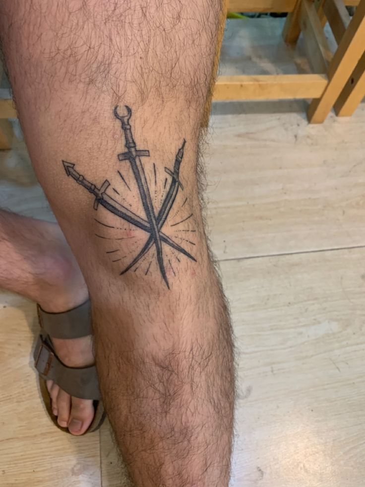 a man's leg with two crossed swords on it