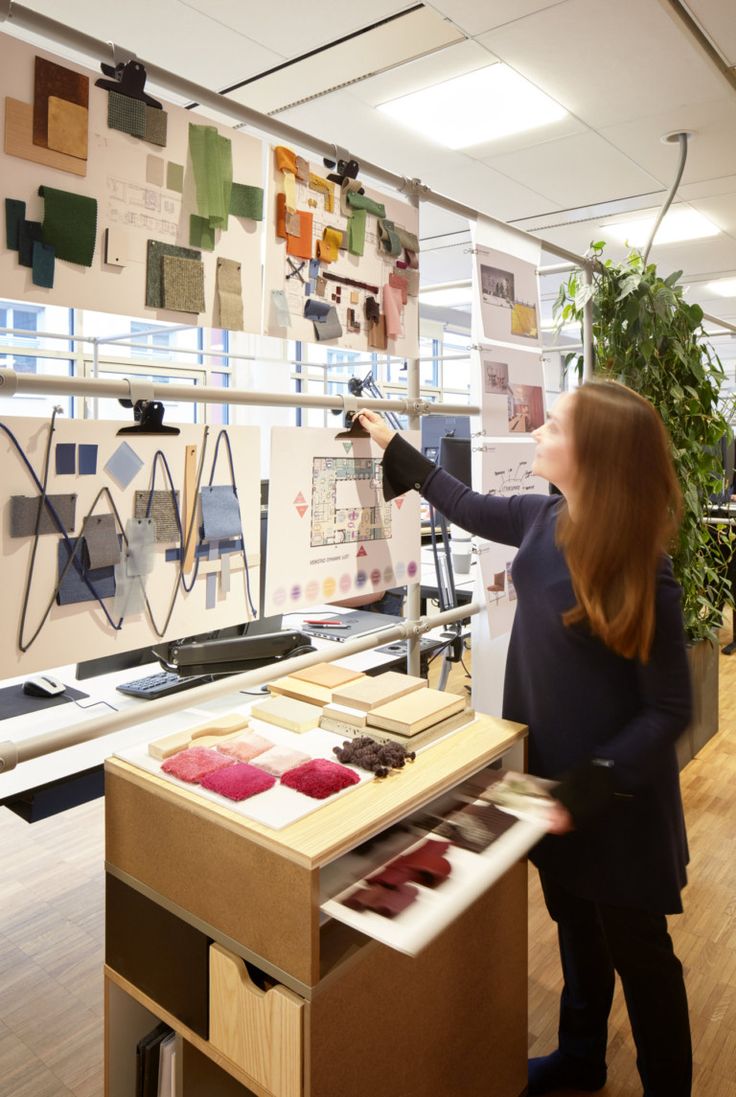 a woman looking at some art work on display in a room with wood flooring