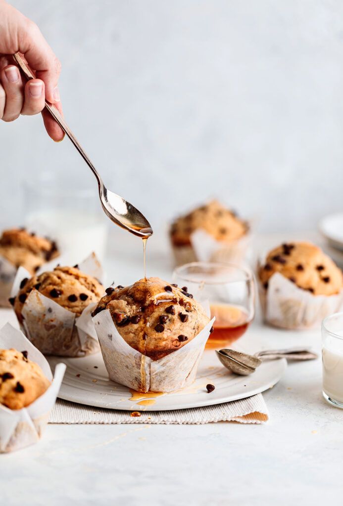 a person holding a spoon over some muffins