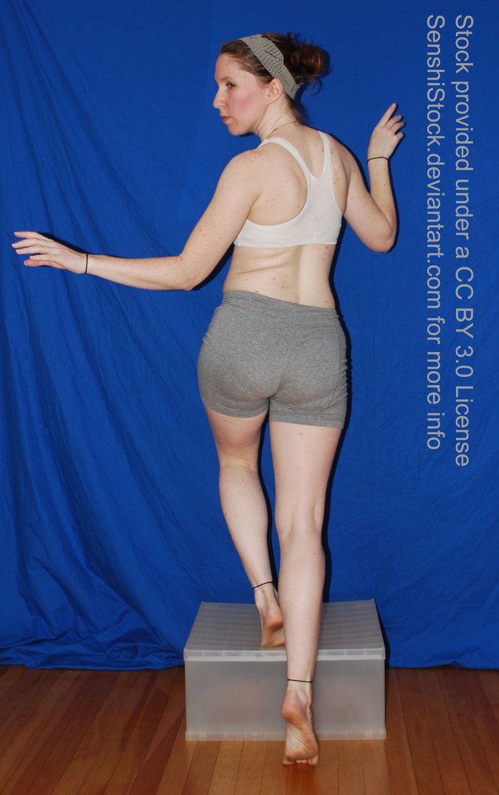 a woman standing on top of a wooden floor next to a blue wall and wearing gray shorts