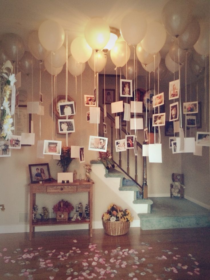 balloons and pictures hang from the ceiling in front of a staircase decorated with confetti