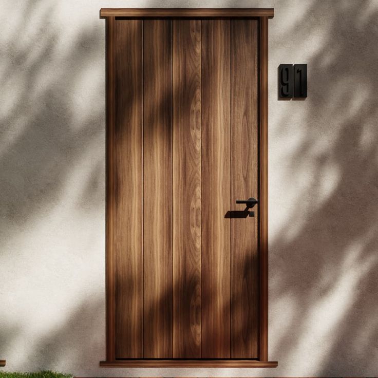 a wooden door is shown in front of a white stucco wall with grass and bushes