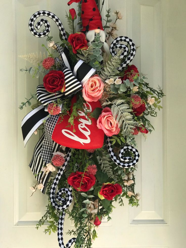 a valentine's wreath hanging on the front door with red roses and black and white ribbons