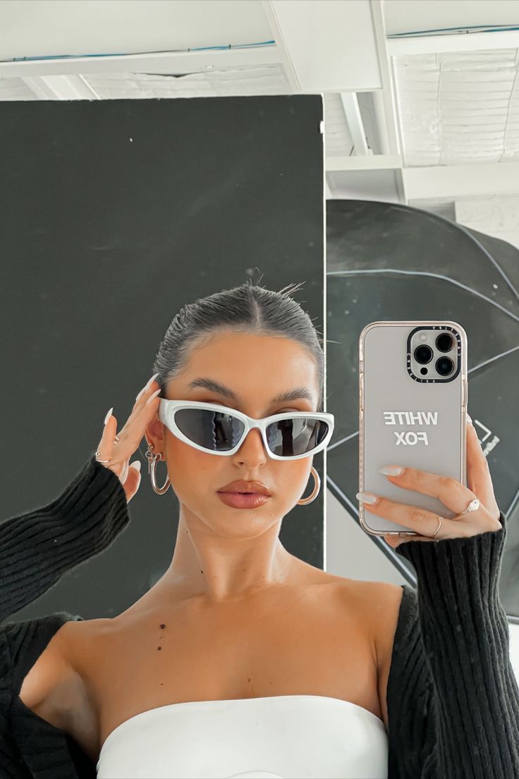 a woman wearing sunglasses holding up her phone