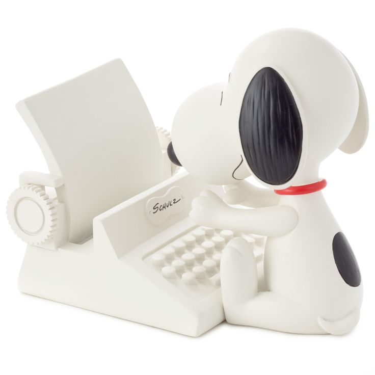 a white dog figurine sitting at a computer