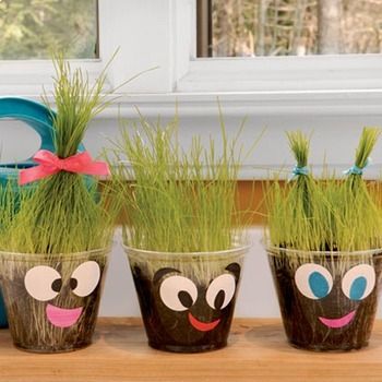 three potted plants with faces painted on them and grass growing out of their mouths